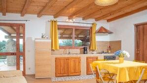 A kitchen with wooden cabinets, a dining table with yellow chairs, and a window with curtains. - Résidence Villa Smeralda Executive – Upscale Apartment with Pool near Olbia (Telti)