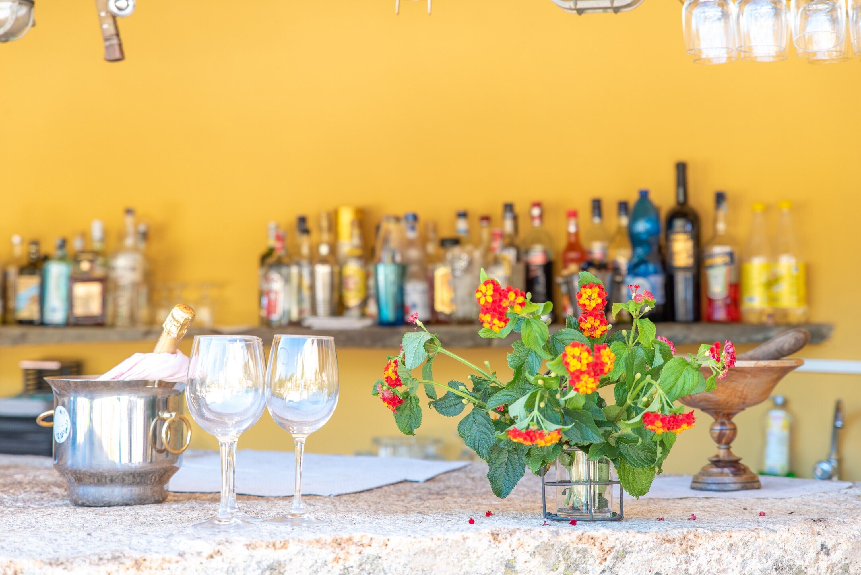 Eine Bar mit einem Metalleimer, zwei Gläsern und einer Vase mit Blumen.