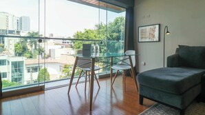 Un salón moderno con balcón de cristal, suelo de madera y sofá verde.
