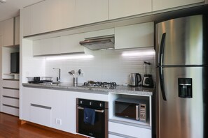 Eine moderne Küche mit weißen Schränken, Edelstahlgeräten, einem Einbauofen, einer Mikrowelle und einem Kühlschrank.