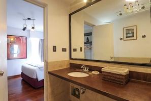 Une salle de bain avec un grand miroir, un lavabo et un petit panier en osier.