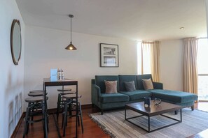 Un salon avec un canapé vert, une table basse et un coin repas comprenant des chaises et une table.