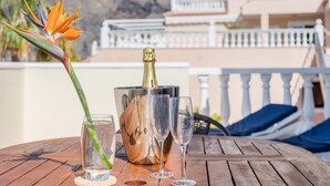 A wooden table with a bottle of champagne, two glasses, and a flower.