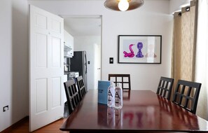 A dining area with a wooden table, chairs, and a framed artwork on the wall. - w* | Bright 3BR with Ocean View (Lima)