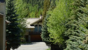 A parking area with a building in the foreground, surrounded by dense forest and a mountain in the background. - Lovin' Life. Near all the Fun Stuff! Now with A/C! (Ketchum)