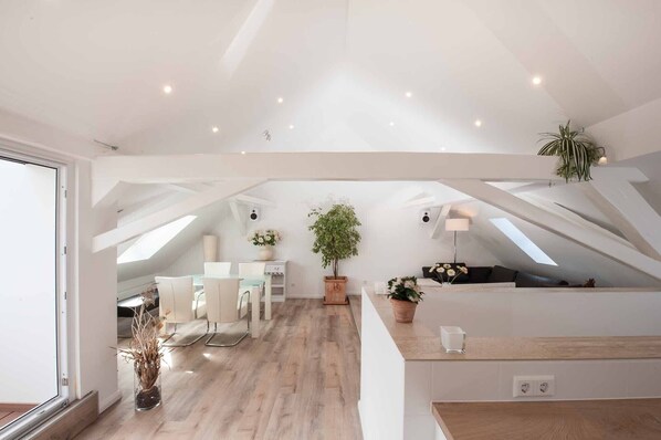 A spacious loft with high ceilings, skylights, a dining area, and a seating area with a view.