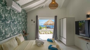 Ein Hotelzimmer mit Bett, Fernseher und Blick auf den Strand.