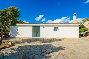 A small white building with a tiled roof, a green door, and a chimney.