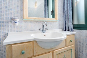A bathroom with a white sink, wooden vanity, and a mirror.