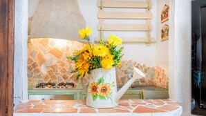 A kitchen with a stone backsplash, a gas stove, and a white kettle with yellow flowers. - Cosy House in Cannigione with Terrace, Mountain Views (Arzachena)