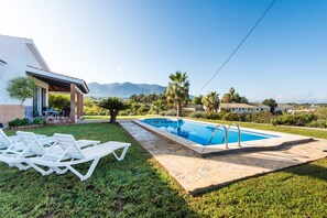Una piscina amb gandules, una zona de terrassa i vista a les muntanyes.