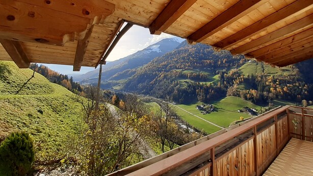 Een houten balkon met uitzicht op een bergachtig landschap.