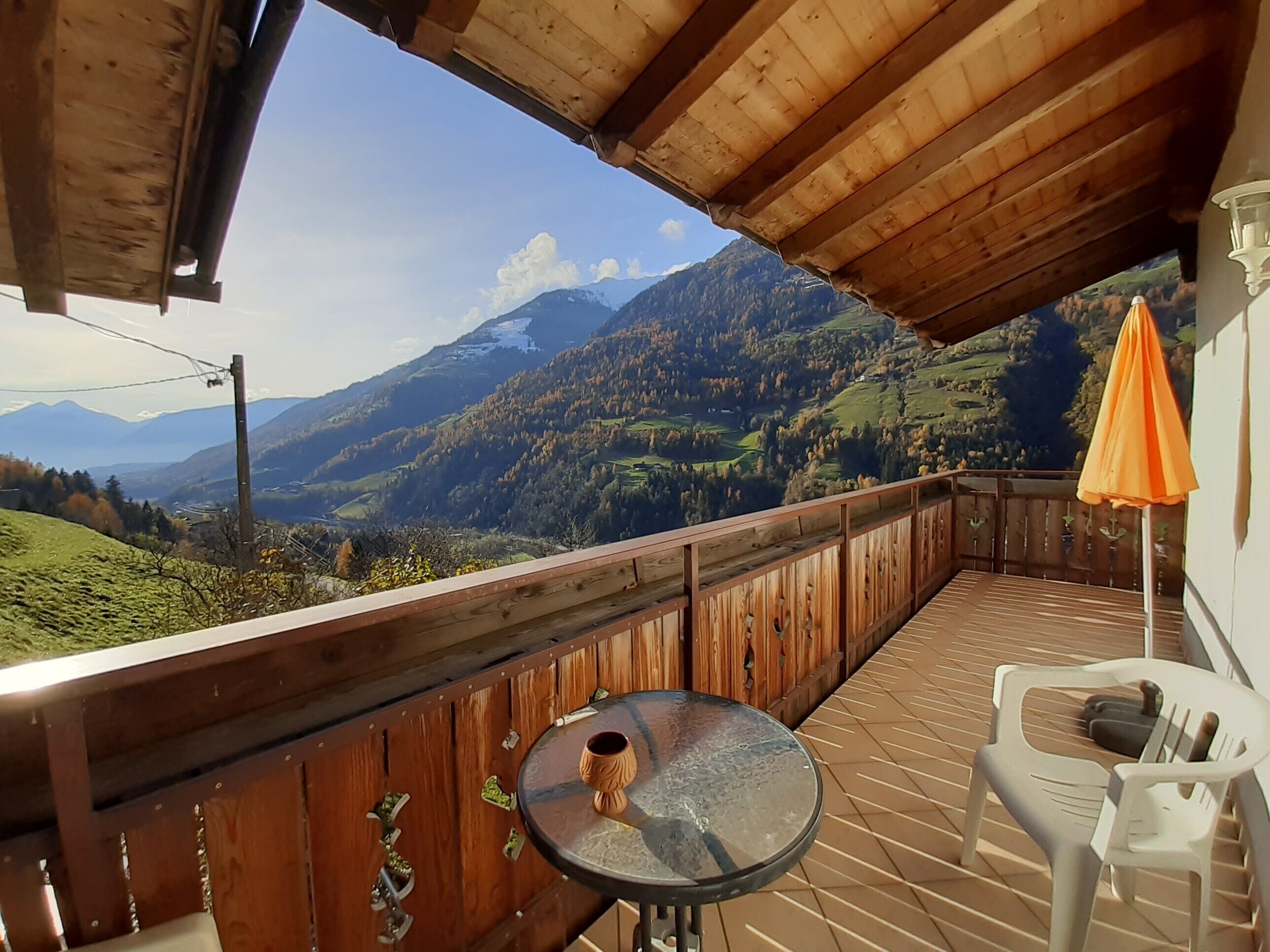 A wooden deck with a table and chairs, overlooking a mountainous landscape.