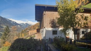 A mountain house with a wooden exterior, a paved driveway, and a view of snow-capped mountains. - Cosy Strickerhof Apartment 2 with Mountain View & Balcony (St. Leonhard in Passeier)