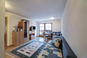 A living room with a sofa, a dining table, and a TV. - Cosy Strickerhof Apartment 2 with Mountain View & Balcony (St. Leonhard in Passeier)
