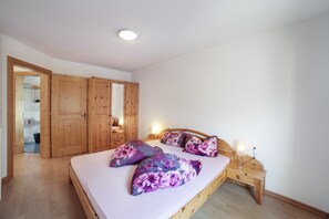 A bedroom with a wooden bed, a nightstand, and a wardrobe. - Cosy Strickerhof Apartment 2 with Mountain View & Balcony (St. Leonhard in Passeier)