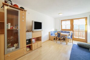 Une pièce comprenant un meuble en bois, un téléviseur, un canapé bleu et une table à manger avec des chaises.