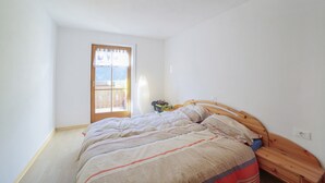 Une chambre avec un lit en bois, une fenêtre donnant sur un beau paysage et un luminaire au plafond.