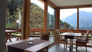 A dining area with large windows, wooden furniture, and a view of mountains. - Holiday Apartment 'Hofschenke Pfeiftal - Bergwiese' with Mountain View (St. Martin in Passeier)