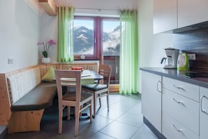 Una cocina con un banco de madera, sillas, una mesa y vistas a montañas a través de una ventana.