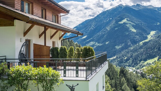 A mountain-view balcony with a wooden house and a mountain backdrop. - Ferienwohnung "Hofschenke Pfeiftal Bergblick" mit Terrasse, Garten & WLAN (St. Martin in Passeier)