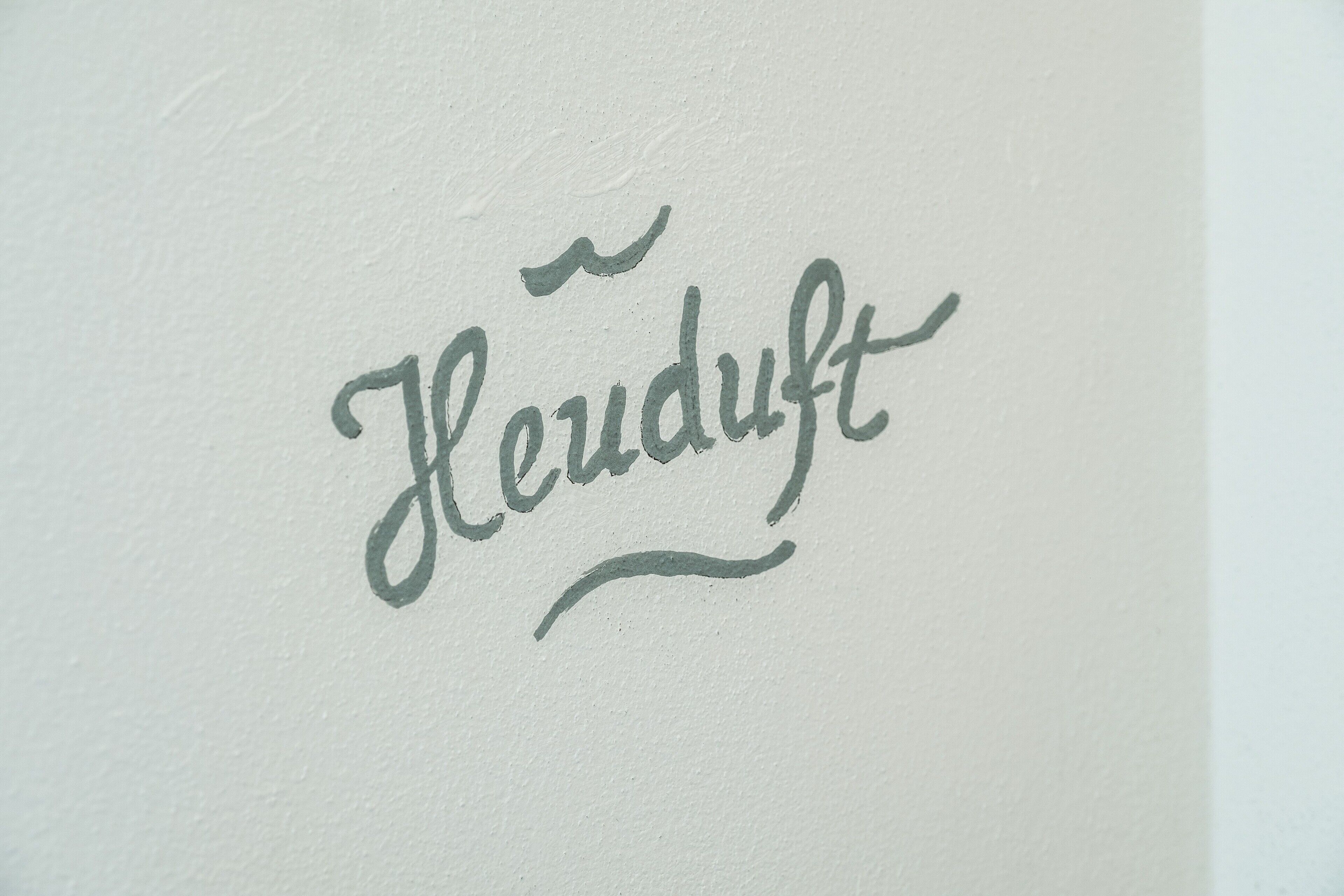 Een handgeschreven bord met de tekst 'Heudt' in sierletters.