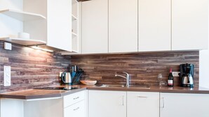 Cozinha moderna com armários brancos, painel de madeira e forno embutido.