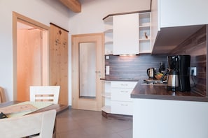 Una cucina moderna con mobili bianchi, una porta in legno e una macchina per il caffè.