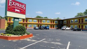 Un motel de varios pisos con un gran letrero que dice Express Inn, que tiene un estacionamiento con varios automóviles.
