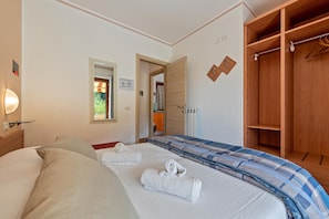 Une chambre à coucher avec un lit, deux serviettes, une armoire en bois et un miroir.