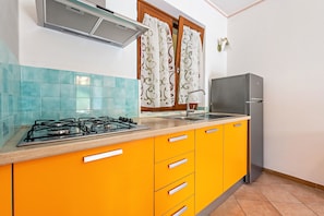 A kitchen with a gas stove, a sink, and a refrigerator.