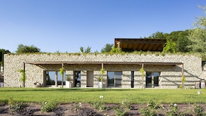 A modern stone building with a flat roof, large windows, and a grassy front yard. - Villa San Francesco - Homelike Villas (Assisi)