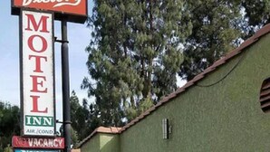 Placa de motel com 'MOTEL' e 'EL INN' visíveis, e uma placa de 'NÃO TEM QUARTOS'.