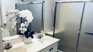Casa de banho com duas pias, um espelho e chuveiro.