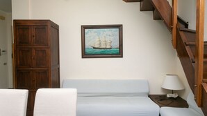 A room with a bed, a wooden wardrobe, a painting of a sailing ship, and a staircase. - M134 - Marcelli, four-room apartment with terrace 50 meters from the sea (Marcelli)