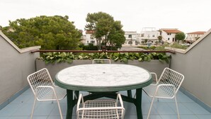 A balcony with a round table and four chairs, overlooking a residential area with trees and buildings. - M134 - Marcelli, four-room apartment with terrace 50 meters from the sea (Marcelli)