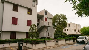 A multi-story residential building with balconies, a parking area, and a trash bin. - M134 - Marcelli, four-room apartment with terrace 50 meters from the sea (Marcelli)