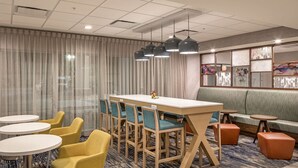 A hotel room with a large window, a dining table with chairs, a sofa, and a small table with a lamp. - Hampton Inn Columbus NE (Columbus)