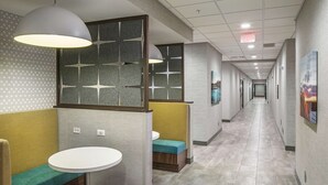 A hotel corridor with seating areas, a round table, and artwork on the walls. - Hampton Inn Columbus NE (Columbus)