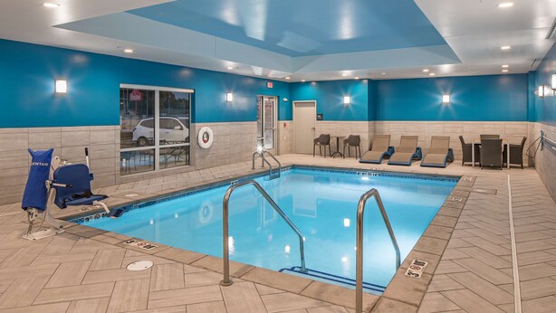 An indoor swimming pool with blue walls, a tiled floor, and a door leading outside. - Hampton Inn Columbus NE (Columbus)
