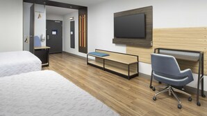 Een hotelkamer met twee bedden, een bureau, een stoel, een televisie en een houten hoofdeinde.