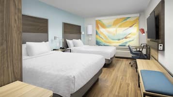A hotel room with two beds, a desk, a chair, a TV, and a large abstract painting on the wall.