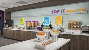 Een ontbijtstation met diverse etenswaren en een bord waarop staat 'TOP IT BREAKFAST'.