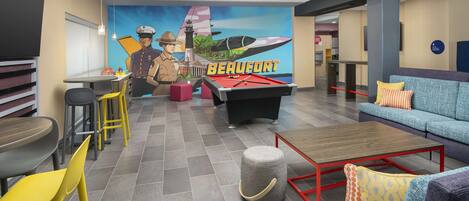 A lounge area with a pool table, seating, and a mural with the word "BEAUFORT".