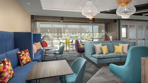 Een moderne lounge met blauwe banken, kleurrijke kussens en een houten tafel.