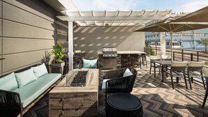 Un patio al aire libre con un sofá, sillas, una parrilla y una zona de comedor.