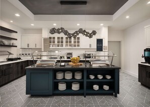 A modern kitchen with a central island, white cabinets, and a geometric patterned floor. - Homewood Suites by Hilton Jackson Fondren Medical District (Jackson)