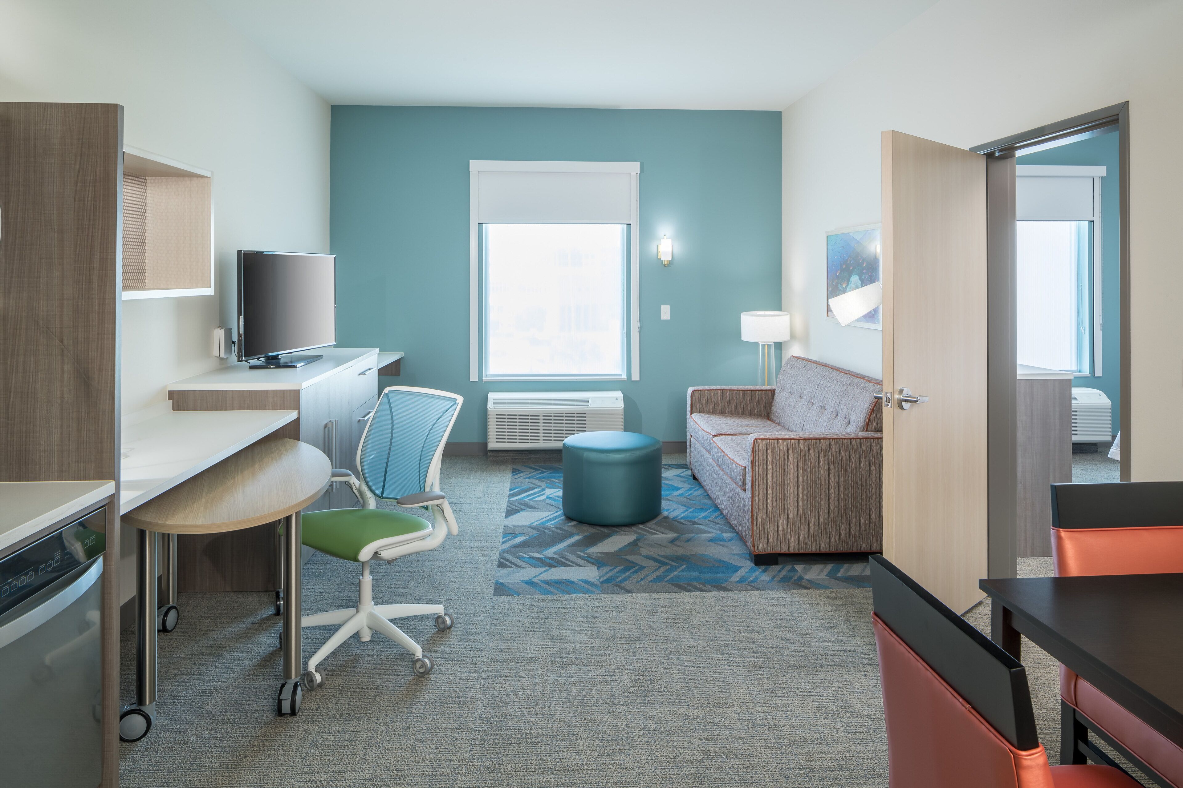 Une chambre d’hôtel moderne équipée d’un bureau, d’une chaise, d’un canapé et d’un téléviseur.