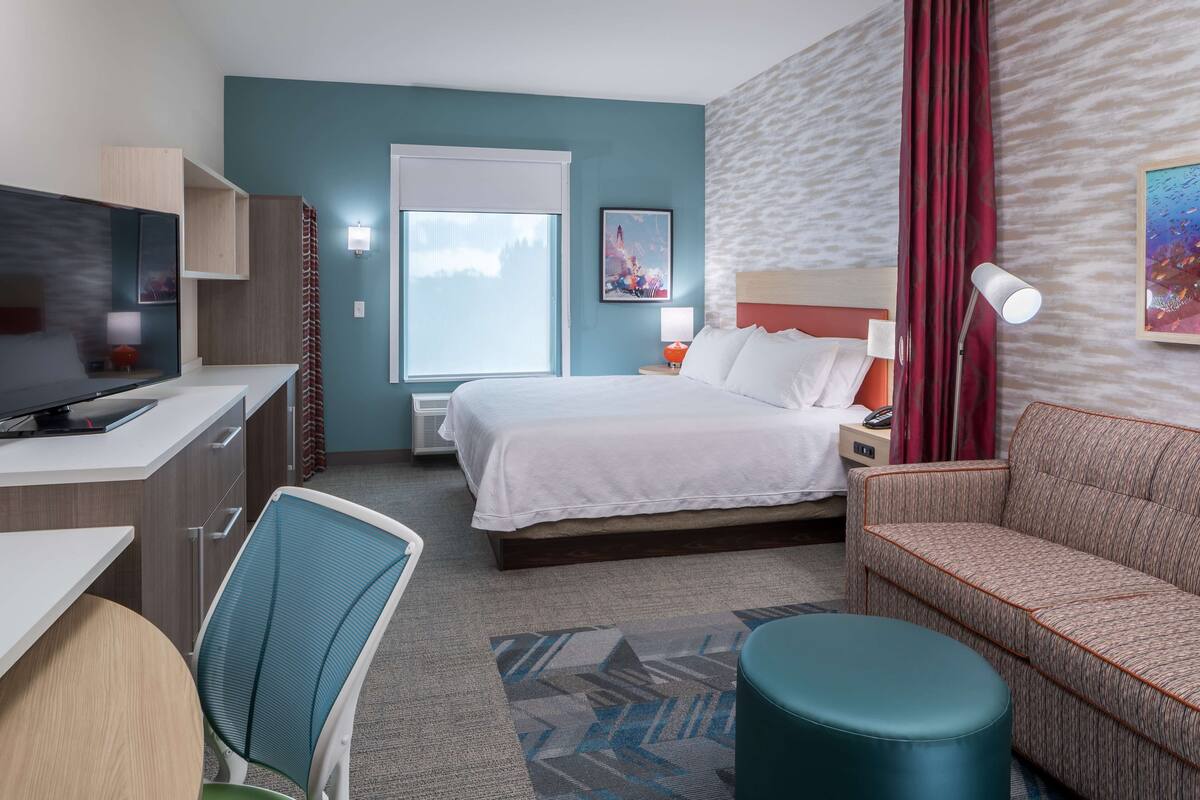 Une chambre d’hôtel équipée d’un lit, d’un bureau, d’une chaise, d’un canapé et d’une télévision.