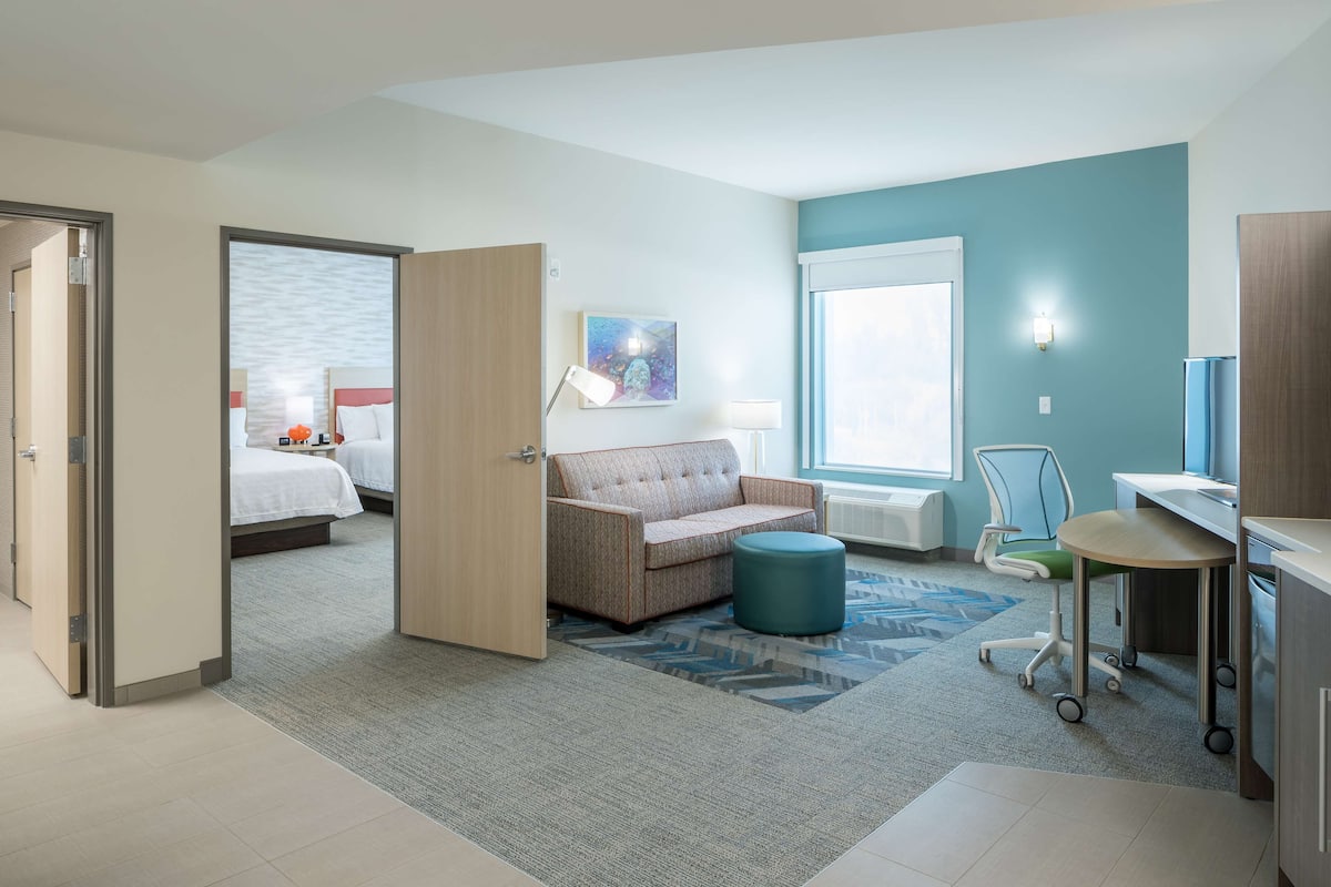 Une chambre d’hôtel avec un lit, un canapé, un bureau et une chaise.